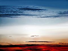 weiße Wolkenschichten vor blauem Himmel im glutroten Sonnenuntergang