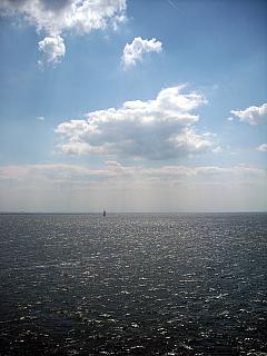 blauer Himmel und weiße Wolken über stahlgrauer glitzernder Nordsee