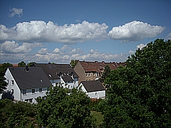 weiße Siedlungs-Häuser vor blauem Himmel mit weißen Wolken
