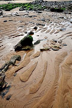 der Gezeitenwechsel hinterlässt Wellen im Sand