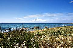 Küste der Insel Noirmoutier mit strahlend blauem Himmel und Wasser und weißen Wellen und Wolken
