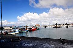 Blick vom Kai der Fischfabrik über den Hafen auf weiße Wolken und blauen Himmel