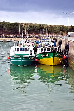 Zwei Fischerboote: ein grüner und ein gelber Fischkutter im Hafen
